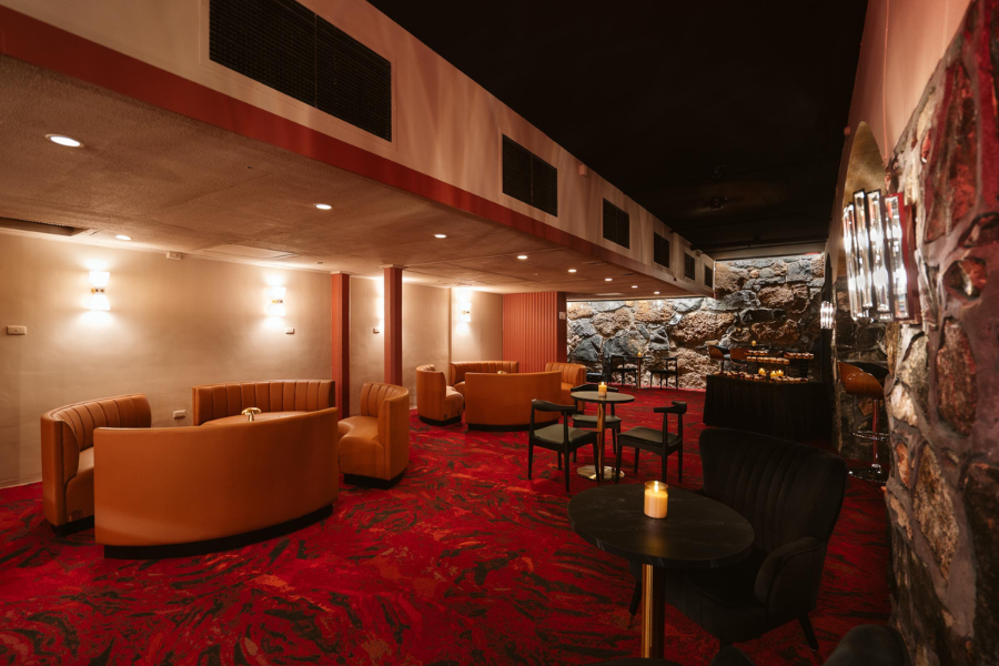 Inside The Ruby Lounge, curved booths and low lighting on patterned red carpet